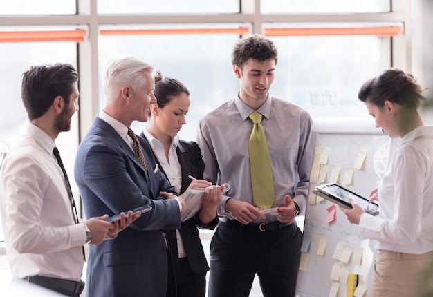 jovem empresário de inicialização fazendo apresentação do projeto ao investidor sênior, grupo de empresários tomando notas e fazendo planos no flip board branco e computador tablet