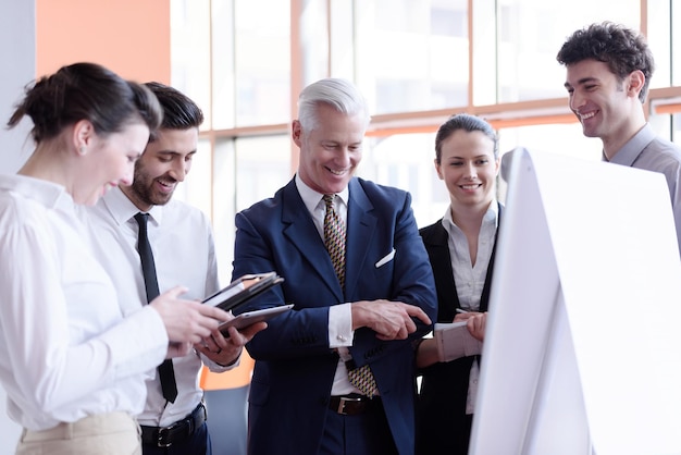 jovem empresário de inicialização fazendo apresentação do projeto ao investidor sênior, grupo de empresários tomando notas e fazendo planos no flip board branco e computador tablet