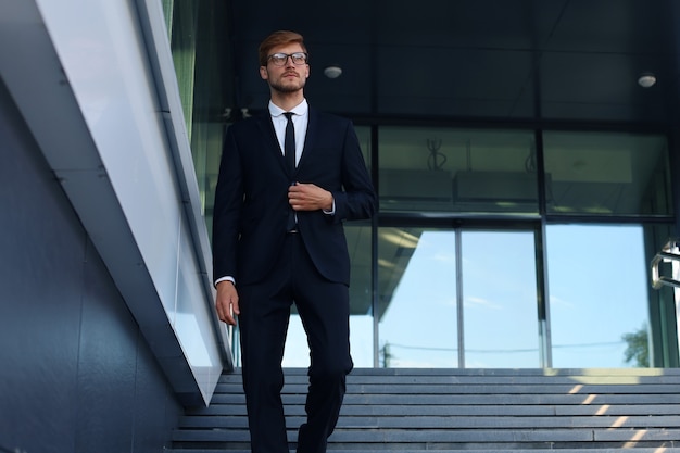 Jovem empresário de sucesso descendo as escadas do lado de fora do prédio de escritórios.