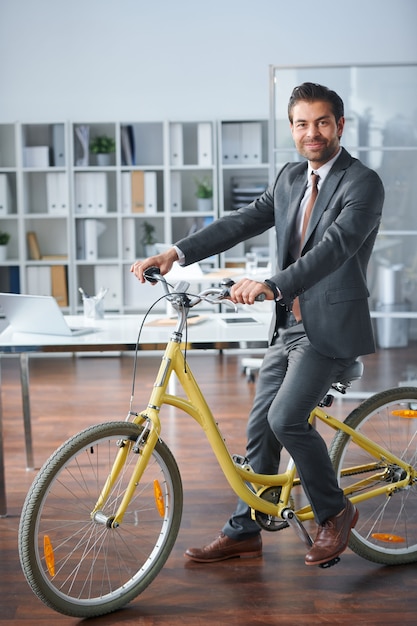 Jovem empresário de sucesso em trajes formais sentado na bicicleta