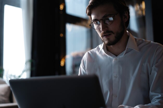 Jovem empresário de sucesso trabalhando em um laptop enquanto está sentado no café.