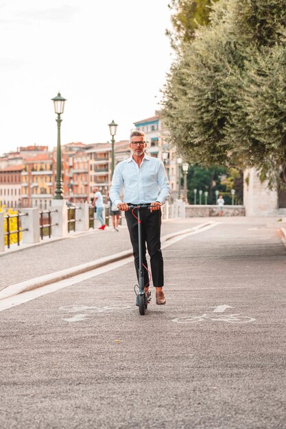 Foto jovem empresário de terno montando uma scooter elétrica enquanto se desloca para o trabalho na cidade