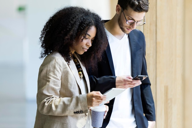 Jovem empresário e empresária usando tablet e smartphone