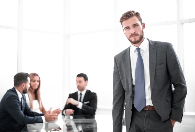 Jovem empresário em pé perto da mesa do escritório