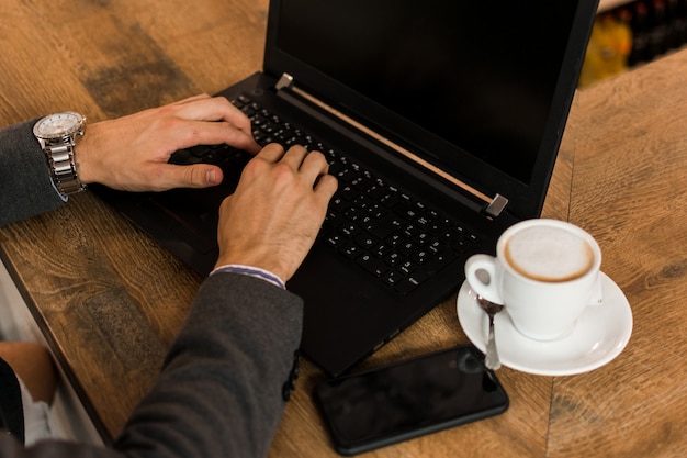 Jovem empresário em um pub, trabalhando com seu laptop. Fechar-se