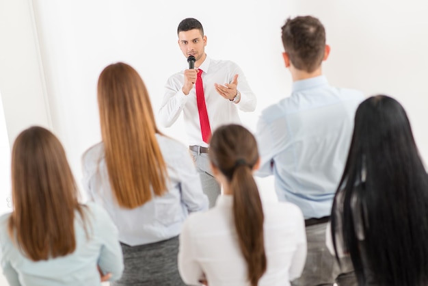 Jovem empresário explicando aos colegas o plano de trabalho. A equipe está ouvindo.