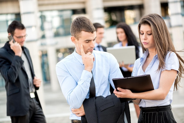 Jovem empresário falando com seu parceiro de negócios de mulher bonita na frente do prédio de escritórios.