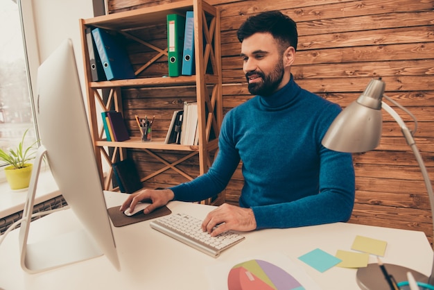 Jovem empresário feliz trabalhando no escritório e digitando no teclado