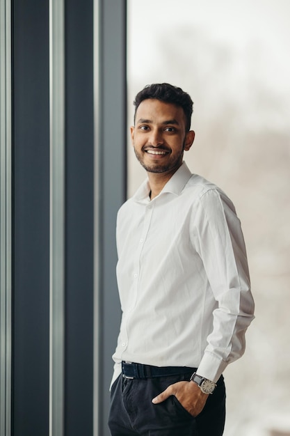 Jovem empresário hindu posando perto da janela do escritório