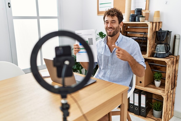 Jovem empresário hispânico fazendo videochamada usando smartphone no escritório.