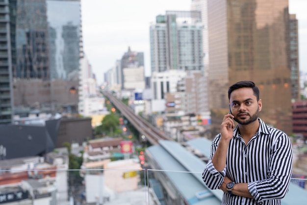 Jovem empresário indiano barbudo contra a vista da cidade