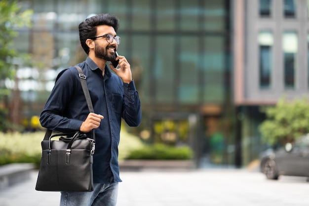 Jovem empresário indiano falando ao telefone enquanto caminhava pela rua