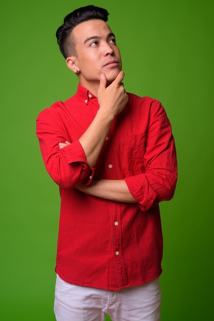 Jovem empresário multiétnico vestindo camisa vermelha contra um fundo verde