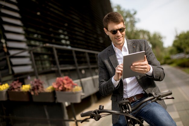 Jovem empresário na ebike com tablet digital