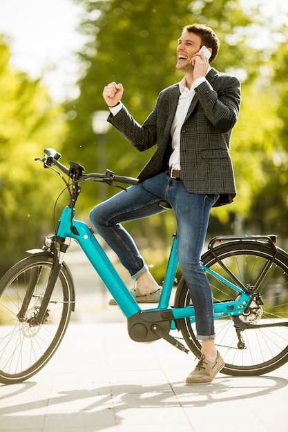 Jovem empresário na ebike usando telefone celular