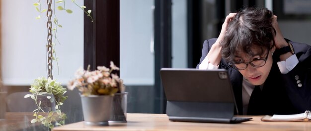 Jovem empresário ou gerente chateado com más notícias recebidas por e-mail senta-se em uma mesa usa laptop