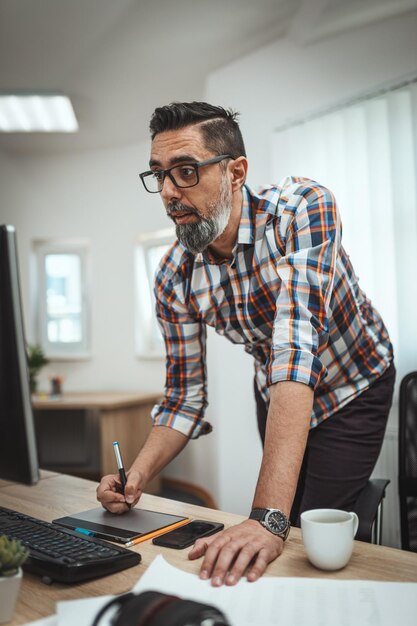 Jovem empresário pensativo sério bonito está trabalhando no computador no escritório.