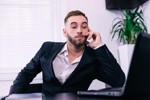 Jovem empresário preocupado trabalhando na mesa no laptop olhando