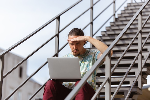 Foto jovem empresário procurando emprego usando laptop ao ar livre