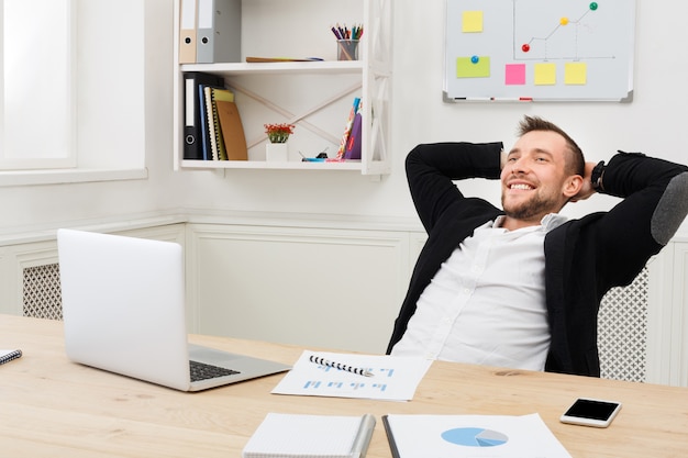 Jovem empresário relaxado com laptop no escritório