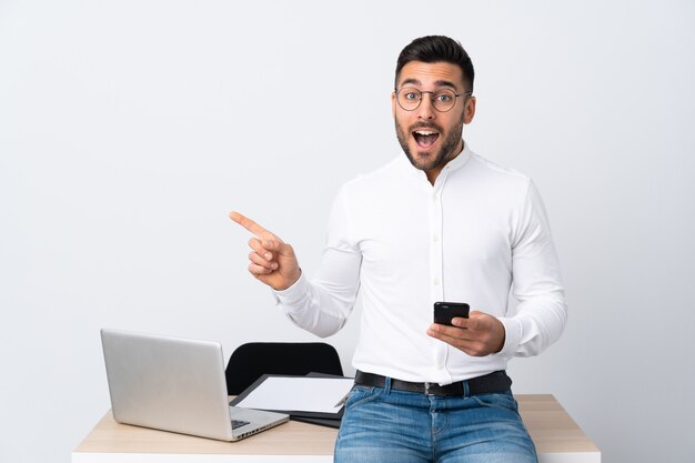 Jovem empresário segurando um telefone móvel, apontando o dedo para o lado