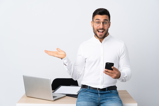 Jovem empresário segurando um telefone móvel, estendendo as mãos para o lado para convidar para vir