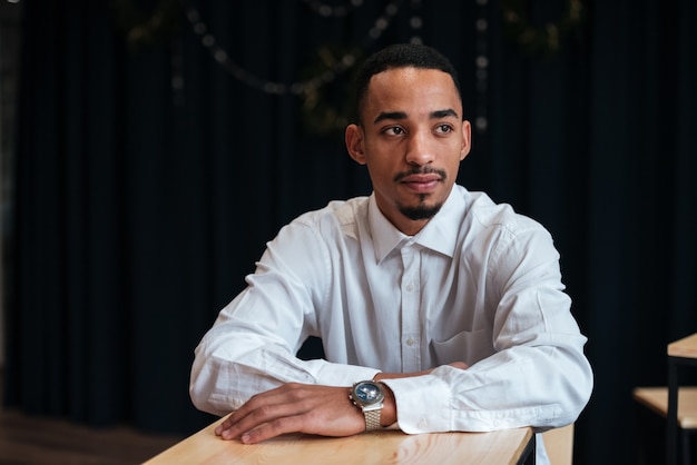 Foto jovem empresário sentado à mesa olhando para o lado