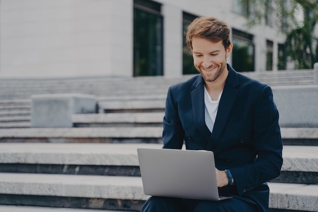 Foto jovem empresário sentado em degraus usa laptop organiza encontro online com investidores