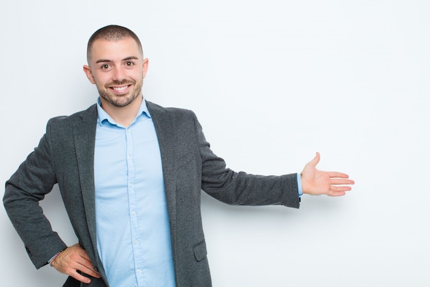 Jovem empresário, sentindo-se feliz e alegre, sorrindo e recebendo você, convidando-o com um gesto amigável na parede plana