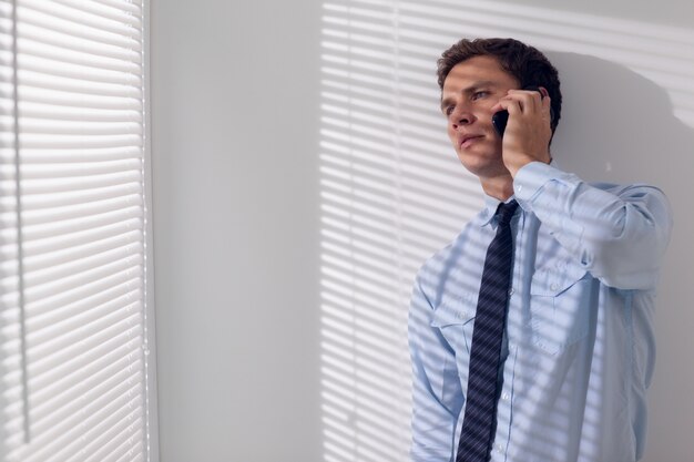 Jovem empresário sério usando o telefone móvel