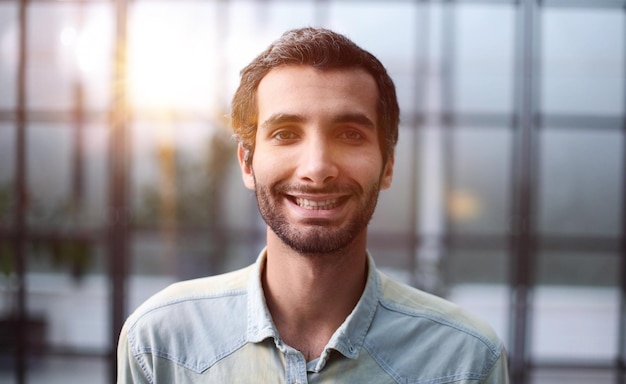 Jovem empresário sorridente confiante em camisa posando para a câmera