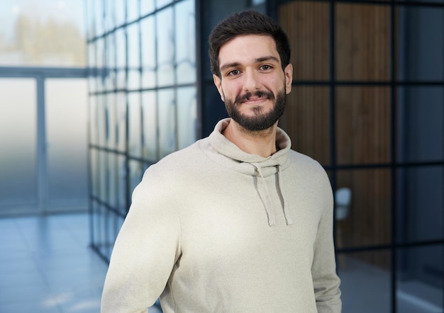 Jovem empresário sorridente em um suéter posando para alcançar o conceito de negócio de riqueza de carreira