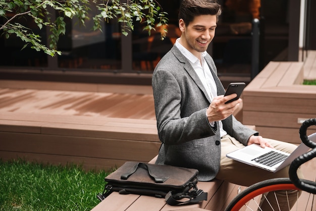 Jovem empresário sorridente usando telefone celular