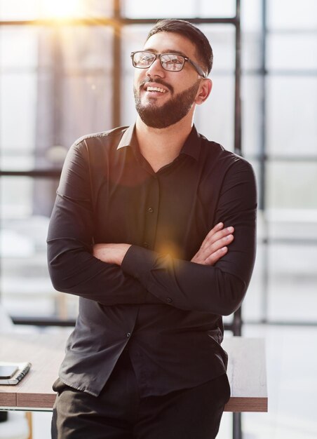 Foto jovem empresário sorrindo no escritório com os braços cruzados