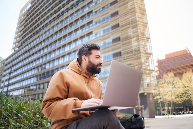 Jovem empresário trabalha com laptop empresário ao ar livre em roupas casuais em um homem de área corporativa.