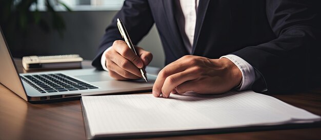 Jovem empresário trabalhando em casa utilizando laptop e bloco de notas para brainstorming