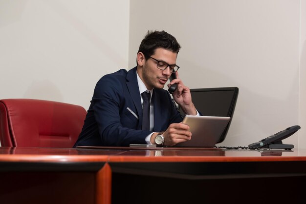 Jovem empresário trabalhando em seu computador enquanto fala ao telefone