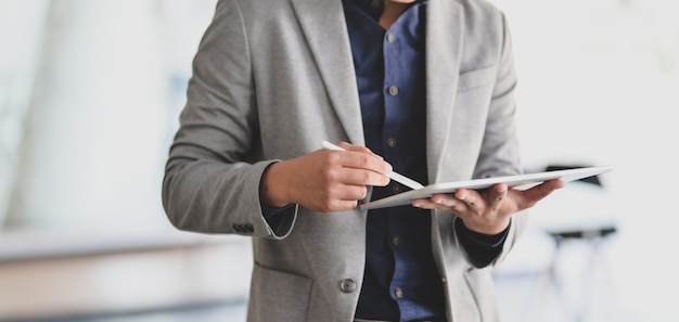 jovem empresário trabalhando em seu projeto enquanto estiver usando tablet digital no escritório moderno