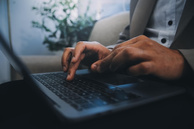 Jovem empresário trabalhando em um escritório sentado em uma mesa olhando para a tela do computador portátil