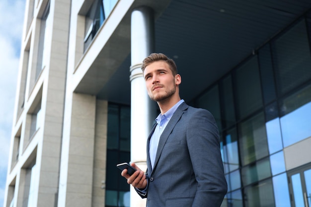 Foto jovem empresário urbano profissional em smartphone, andando na rua usando telefone celular.