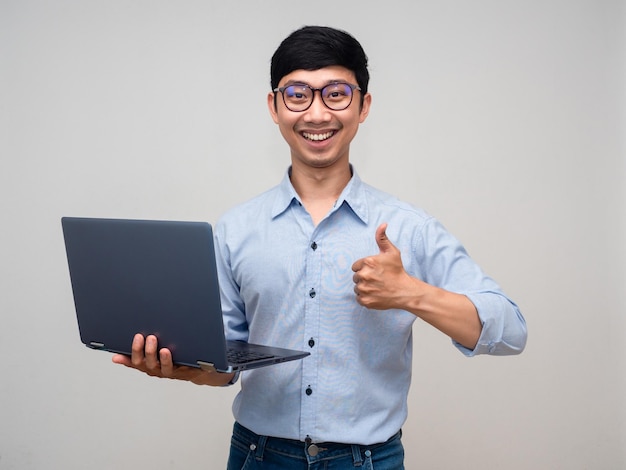 Jovem empresário usa óculos sorriso alegre segurando laptop mostra polegar para cima isolado