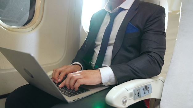 Jovem empresário usando laptop em avião