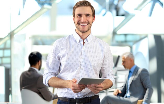 Foto jovem empresário usando seu tablet no escritório