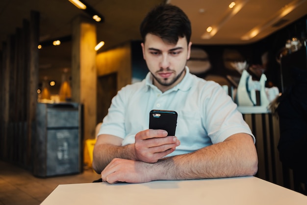 Jovem empresário, usando telefone celular em um café