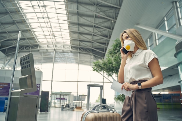 Jovem encantada falando ao telefone enquanto espera seu colega para uma viagem de negócios