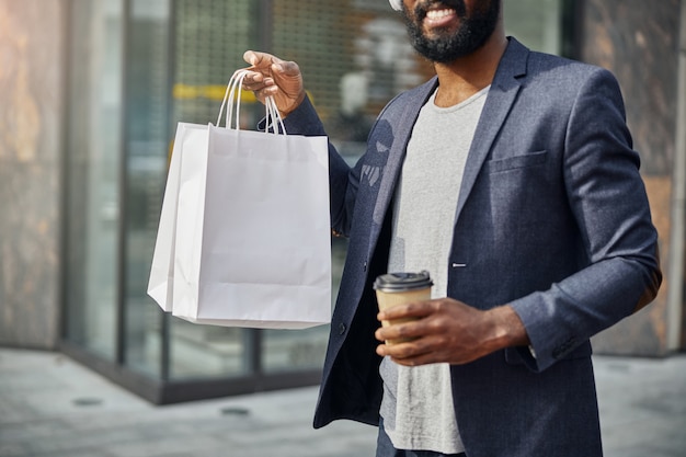 Jovem encantado com café na mão enquanto vai fazer uma pausa ao ar livre