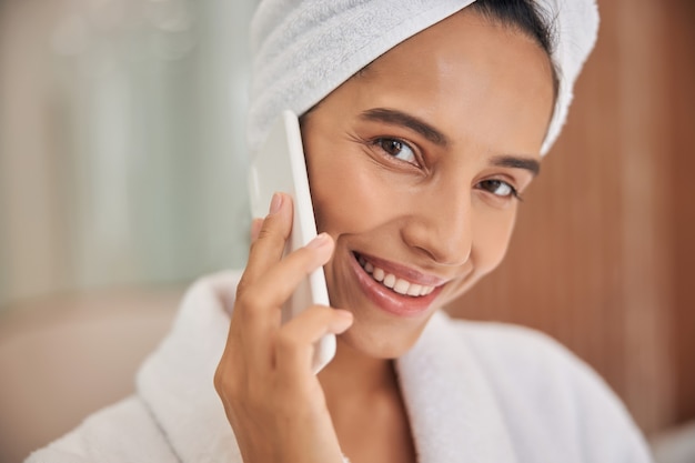 Jovem encantadora falando no celular depois do banho