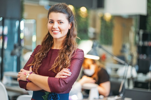 Jovem encantadora mulher sorridente proprietário da barra de unha do salão de beleza, conceito de própria empresa