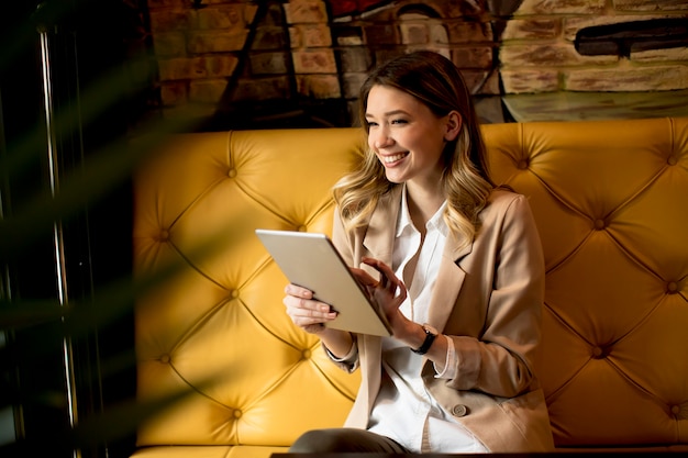 Jovem encantadora sorridente com tablet digital no café