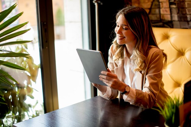 Jovem encantadora sorridente com tablet digital no café